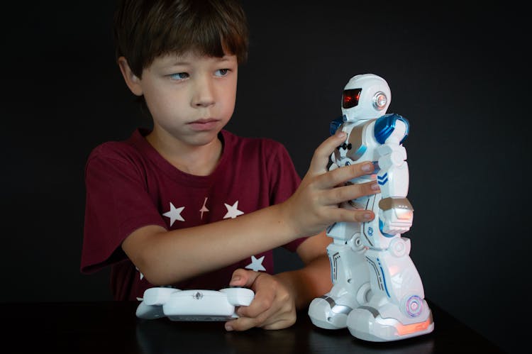 Boy In Red T-shirt Holding White And Blue Robot Toy