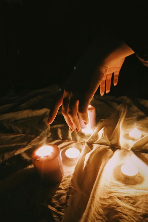 Free A warm atmosphere created by candlelight, highlighting delicate hands reaching towards the flames. Stock Photo