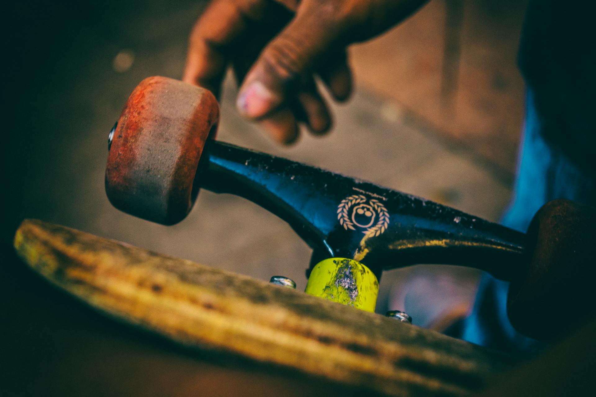 Detail shot of skateboard trucks and wheels with a hand, showcasing urban skate culture.