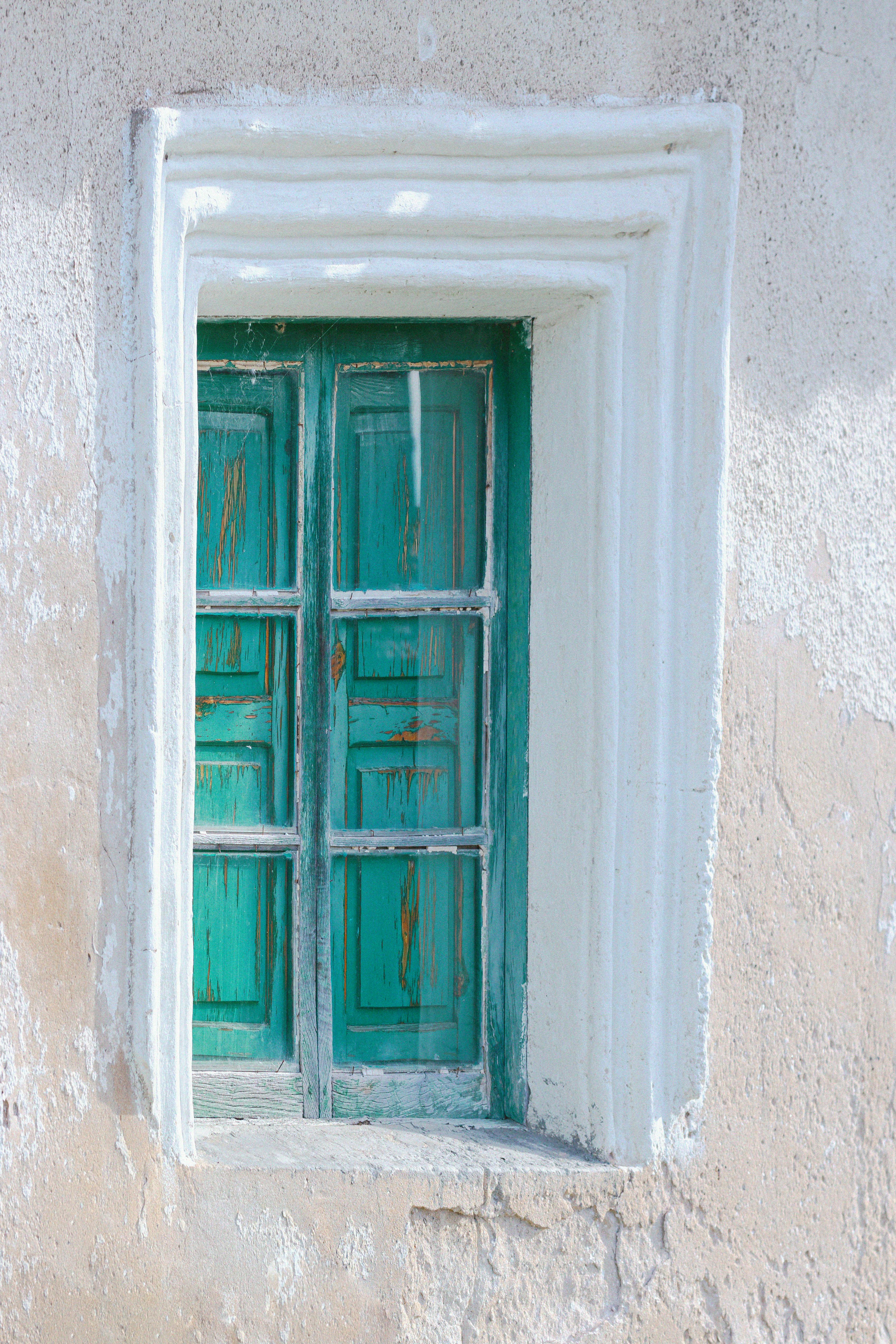 Captivating rustic green window set in a weathered concrete wall, displaying vintage charm.