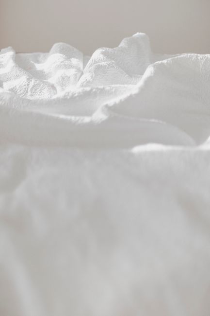 Minimalist close-up of crumpled white textured fabric in gentle light.