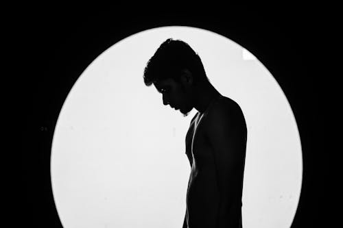 Free Artistic black and white silhouette of a shirtless man with dramatic lighting. Stock Photo