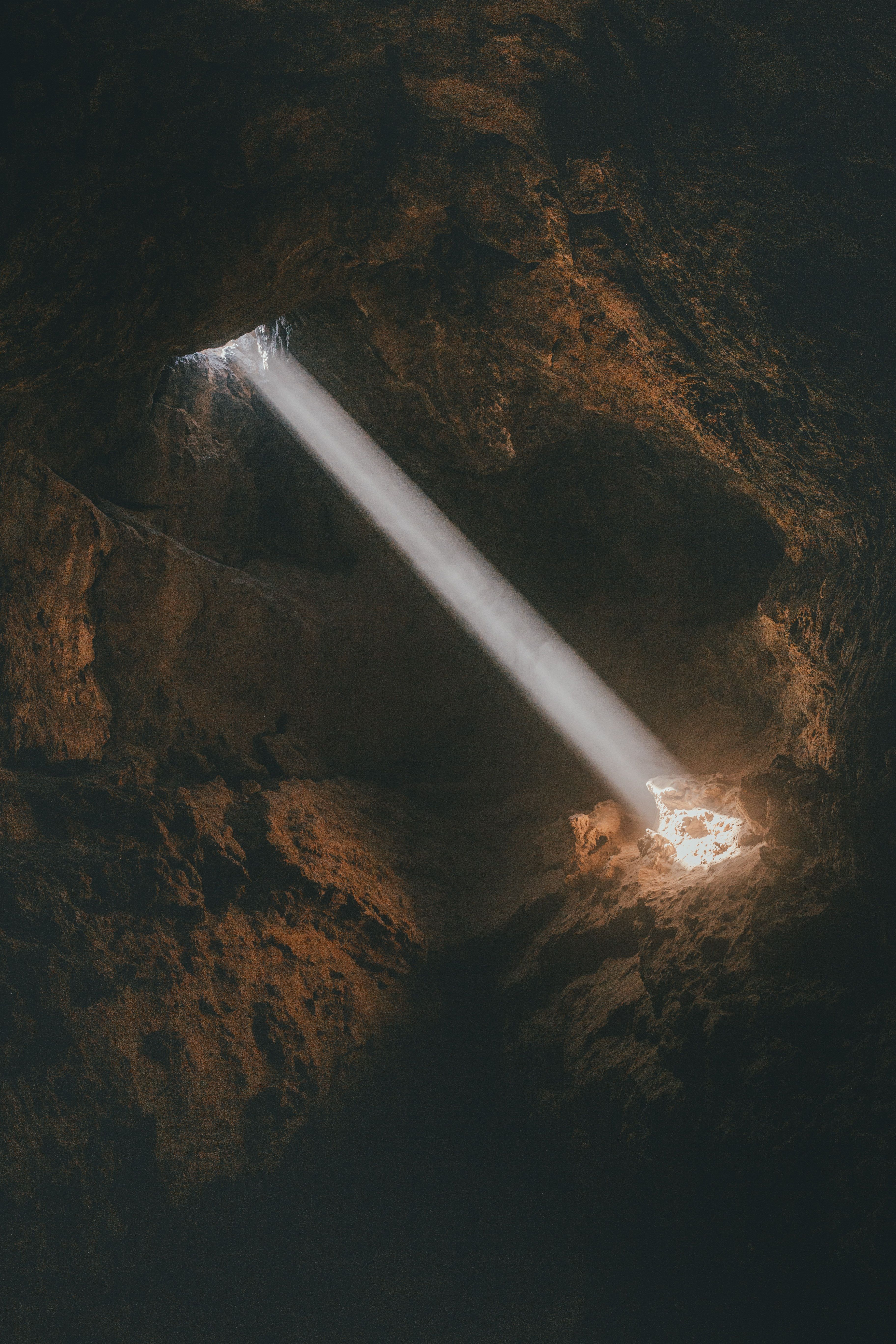 A striking beam of sunlight piercing through a rocky cave formation, creating a mystical ambiance.