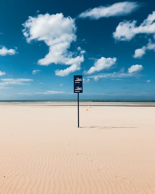 Free Signage in a White Sand Beach under Clouds and Blue Sky Stock Photo