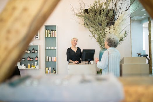A senior woman conversing with a hairdresser at a stylish salon reception desk.
