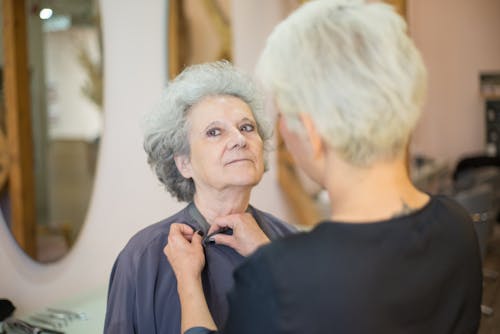 A Person Buttoning the Black Cape the Elderly Woman is Wearing