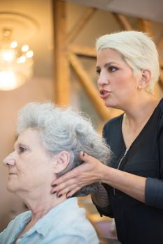 Hairdresser providing a haircut to an elderly woman in a salon setting.