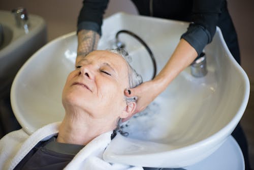 Free Person in Black Long Sleeves Washing the Hair of the Customer Stock Photo