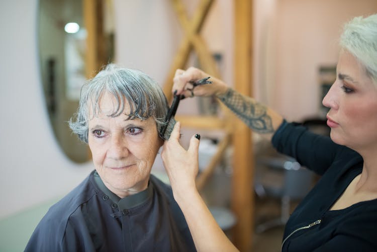 A Stylist Cutting The Hair Of The Elderly Woman