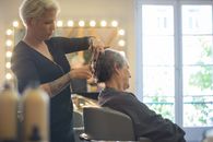Hairdresser expertly trims senior client's hair in well-lit salon setting, focusing on precision.