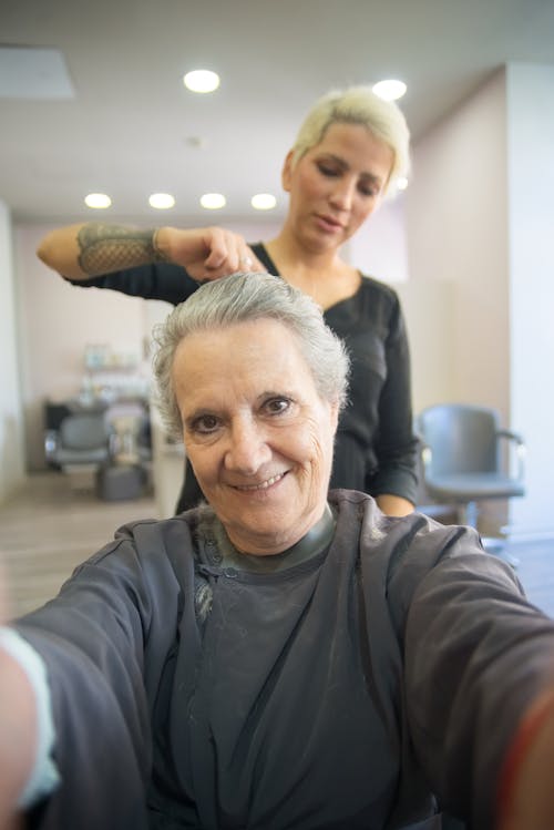 Free A Woman Combing the Hair of the Elderly Woman Smiling at the Camera Stock Photo