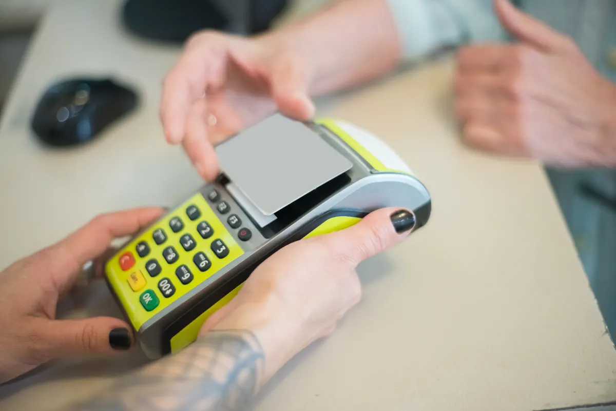 Person using a smartphone to scan a store receipt for price drops, with a downward financial graph nearby.