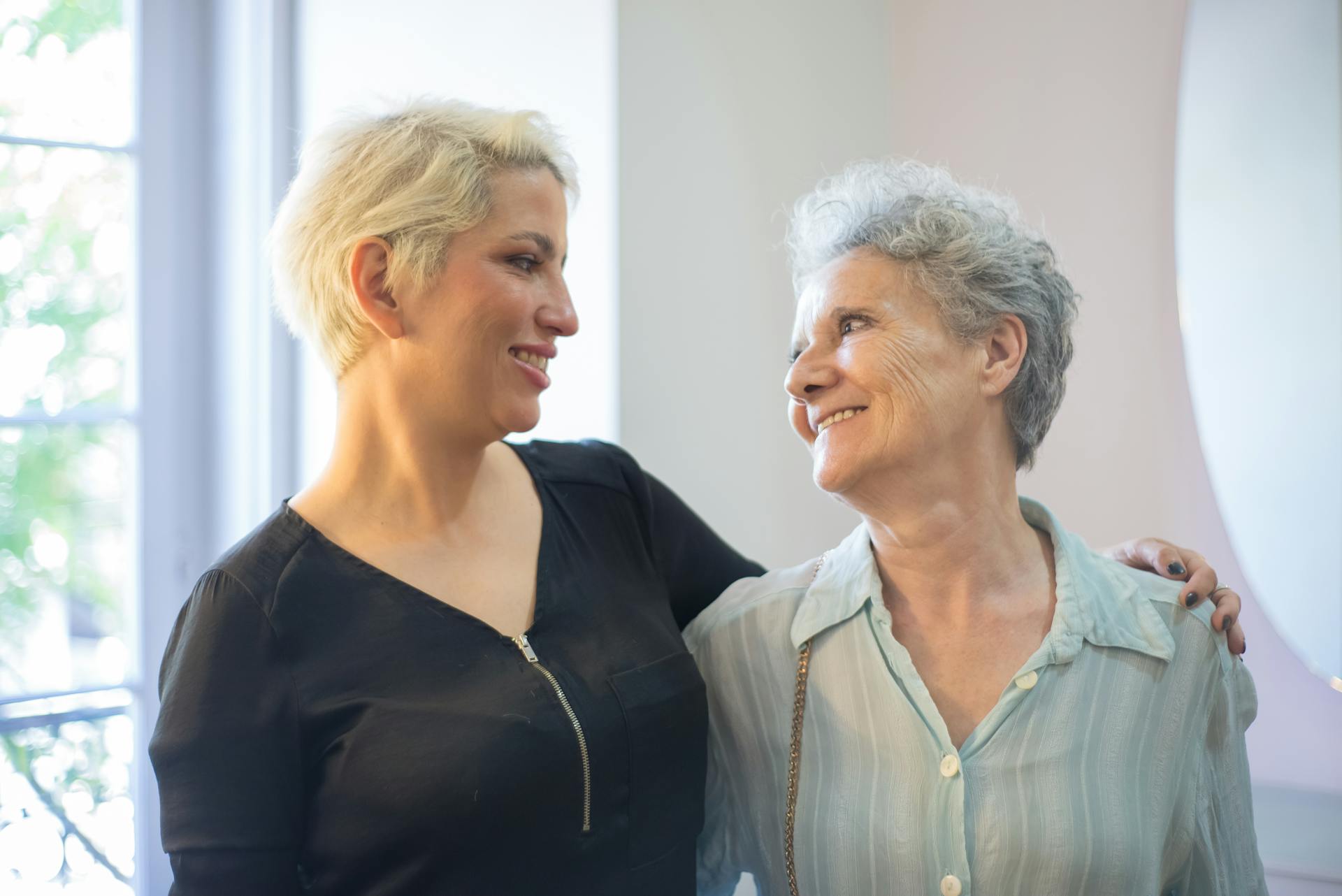 Senior woman enjoying a haircut and friendly conversation with hairdresser indoors.