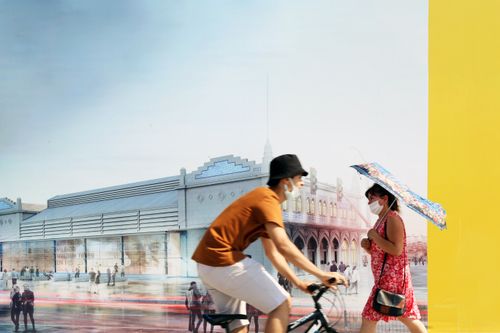 Free A cyclist and pedestrian wearing masks in front of a building mural. Stock Photo