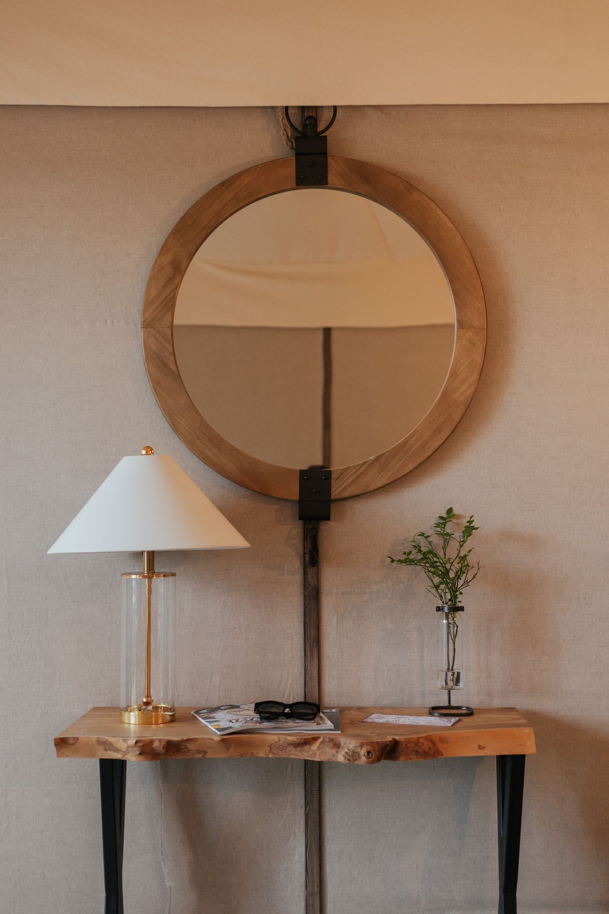 Wooden console table with round mirror, modern lamp and decorative objects