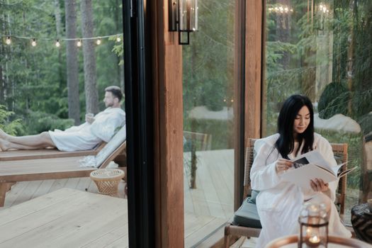 Couple enjoying relaxation in a forest retreat, reading and lounging outdoors.