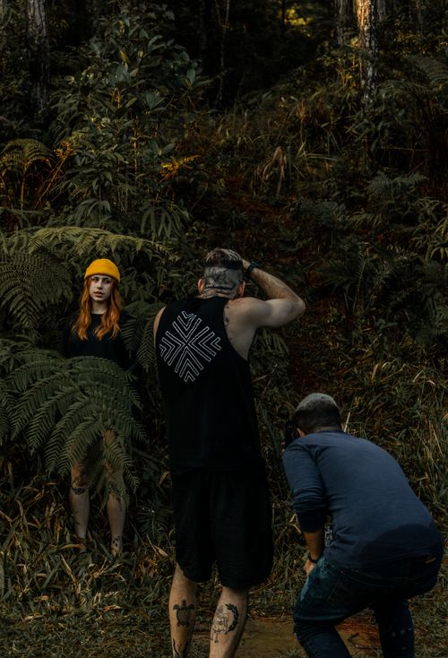 Free Photographers at work capturing a model in a dense forest landscape, featuring vibrant greenery. Stock Photo