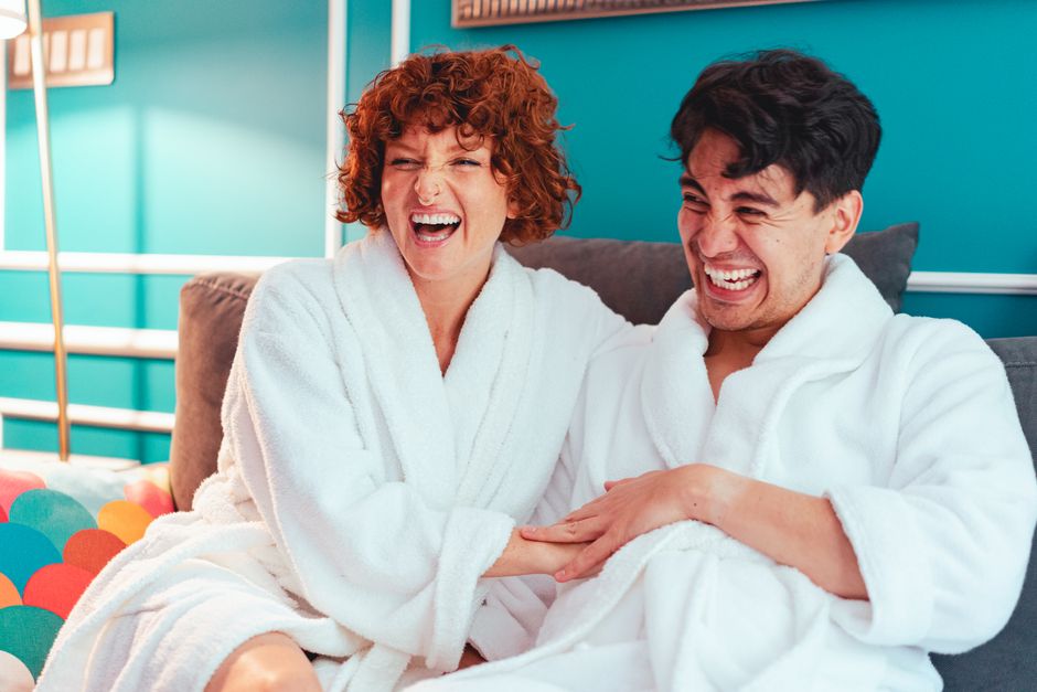 couple laughing together on a sofa - what does enhance intimacy mean couple laughing together on a sofa - what does enhance intimacy mean