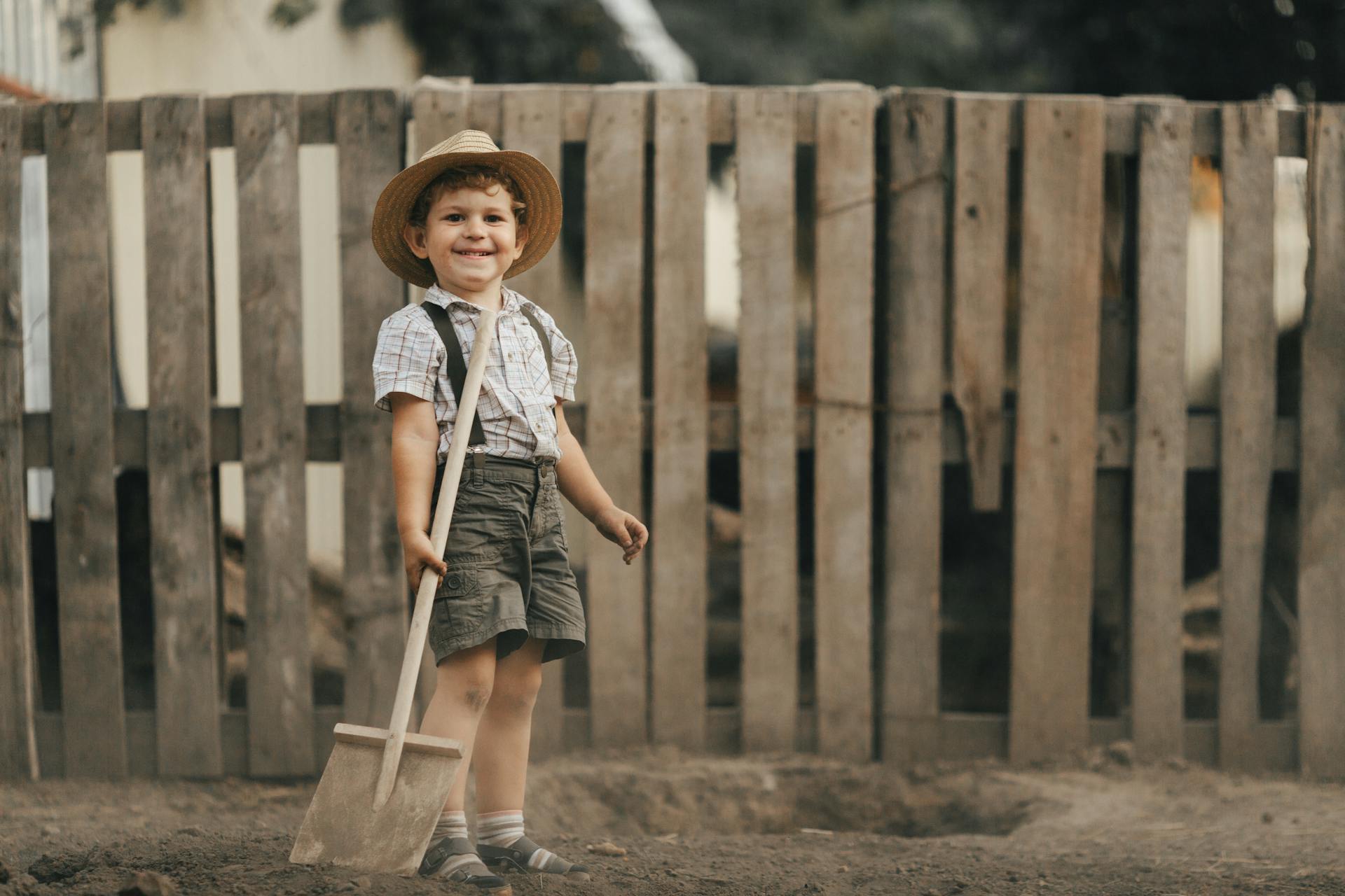 Young Boy Holding a Wooden Shovel in a Yard