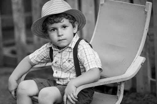 Grayscale Photo of a Cute Boy Wearing a Hat