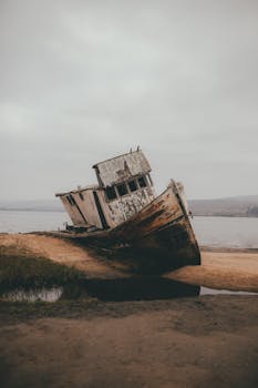 A hauntingly beautiful image of an abandoned shipwreck on a misty beach, evoking a sense of mystery and history.