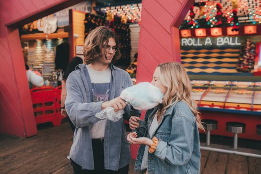 Girl Eating Cotton Candy that Her Boyfriends is Holding 