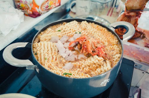 Close-Up Photo of a Pot with Noodles and Kimchi