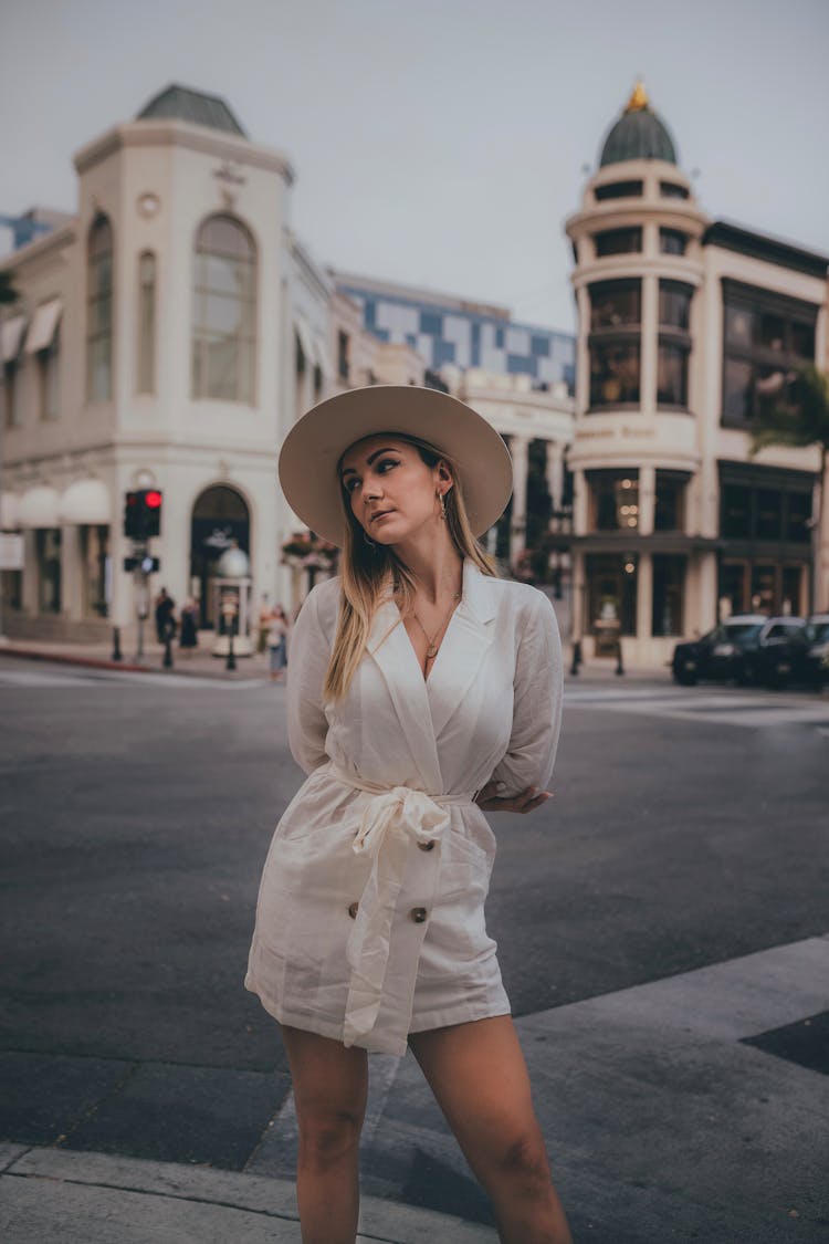 Woman Wearing A Round Hat Standing On A City Street 