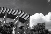 这张黑白照片中，现代建筑与云、树相映成趣