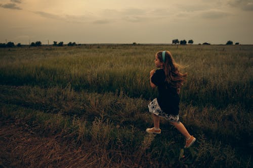 Photo of a Girl in a Black Shirt Running on a Field