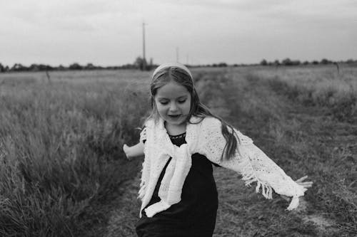 Monochrome Photo of a Cute Girl on a Field with Grass