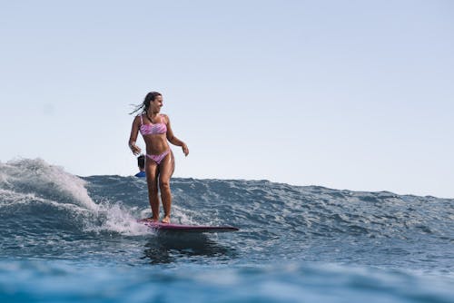 Woman in Pink Bikini Surfing on Sea Waves
