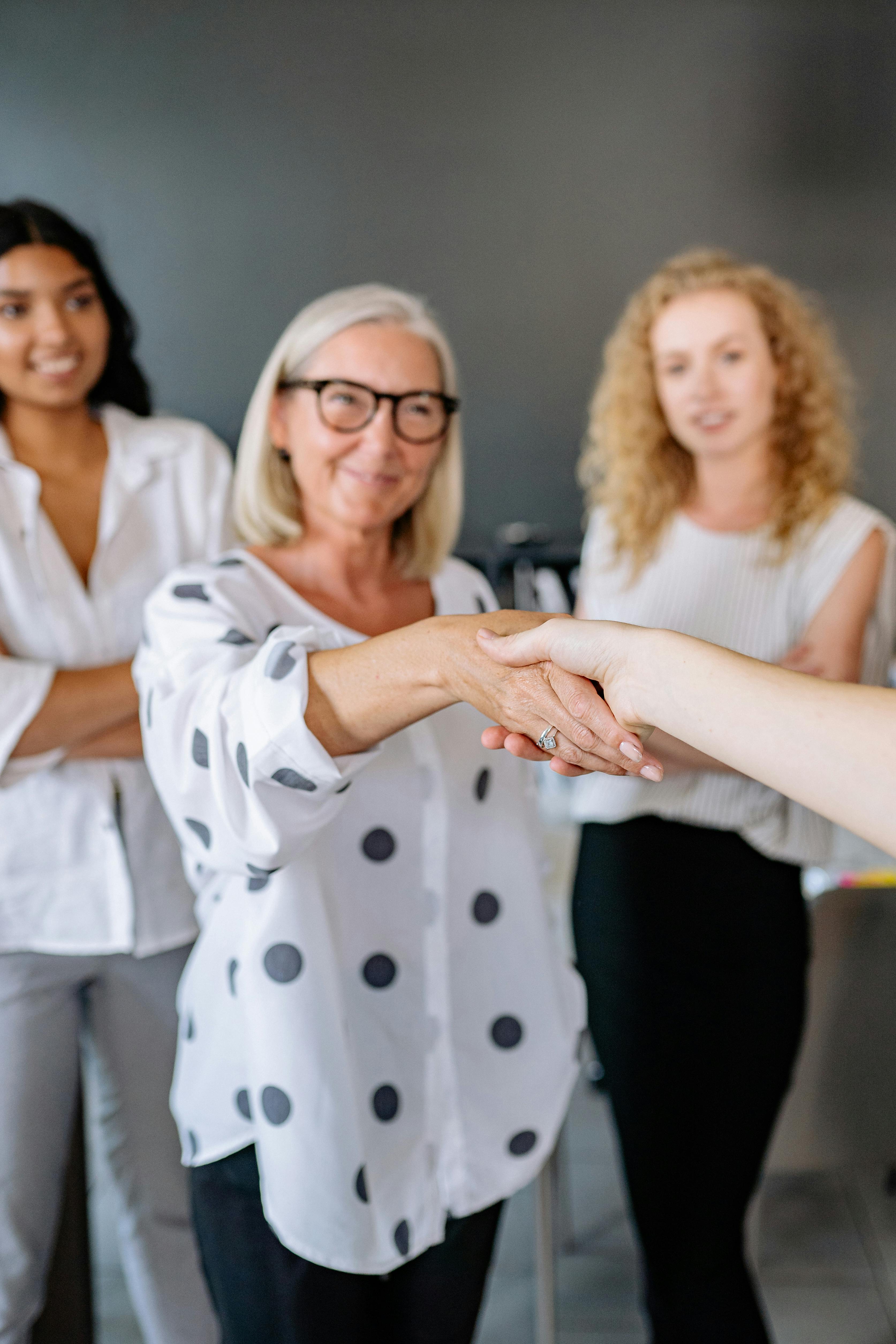 gray haired woman shaking hands with a person