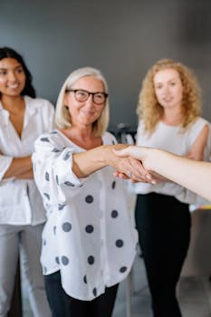 Diverse group of businesswomen shaking hands, symbolizing cooperation and teamwork in the office.