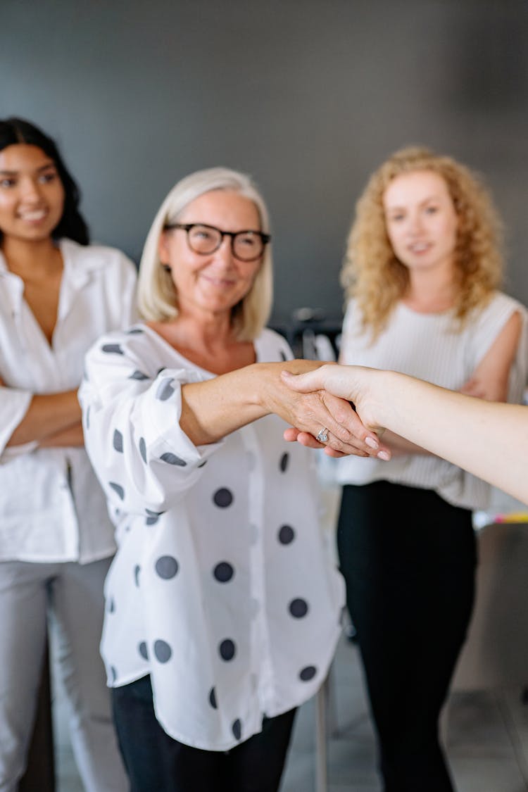 Gray Haired Woman Shaking Hands With A Person 