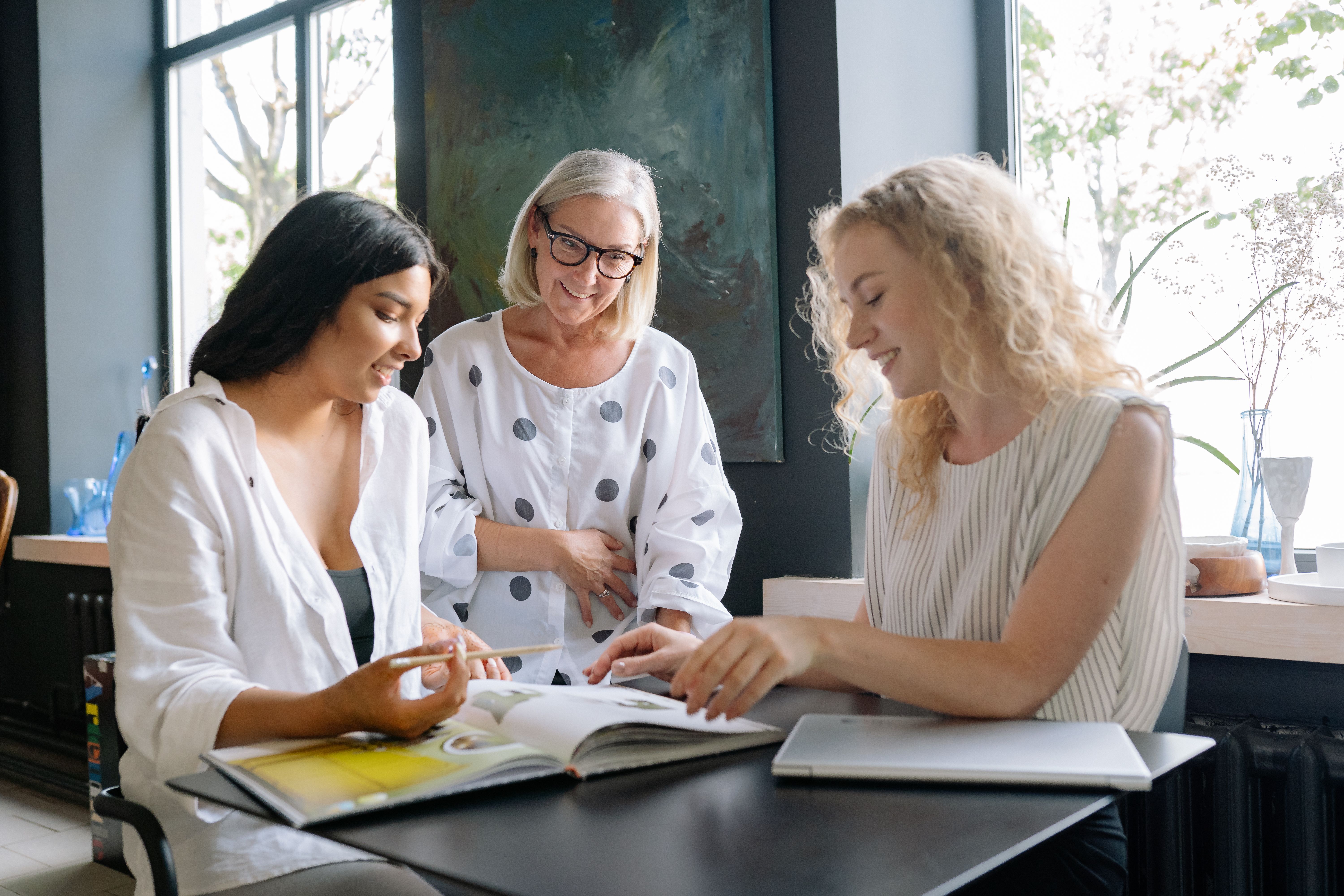 Three diverse businesswomen engaged in a collaborative meeting at a modern office space, showcasing teamwork.