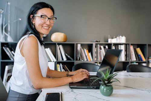 Free Woman Using a Laptop and Smiling at the Camera Stock Photo