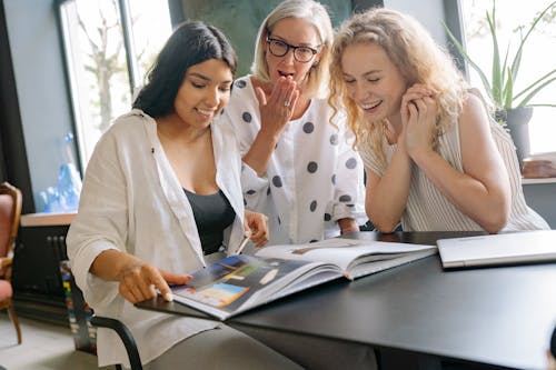 Free Women Looking at a Magazine Together Stock Photo