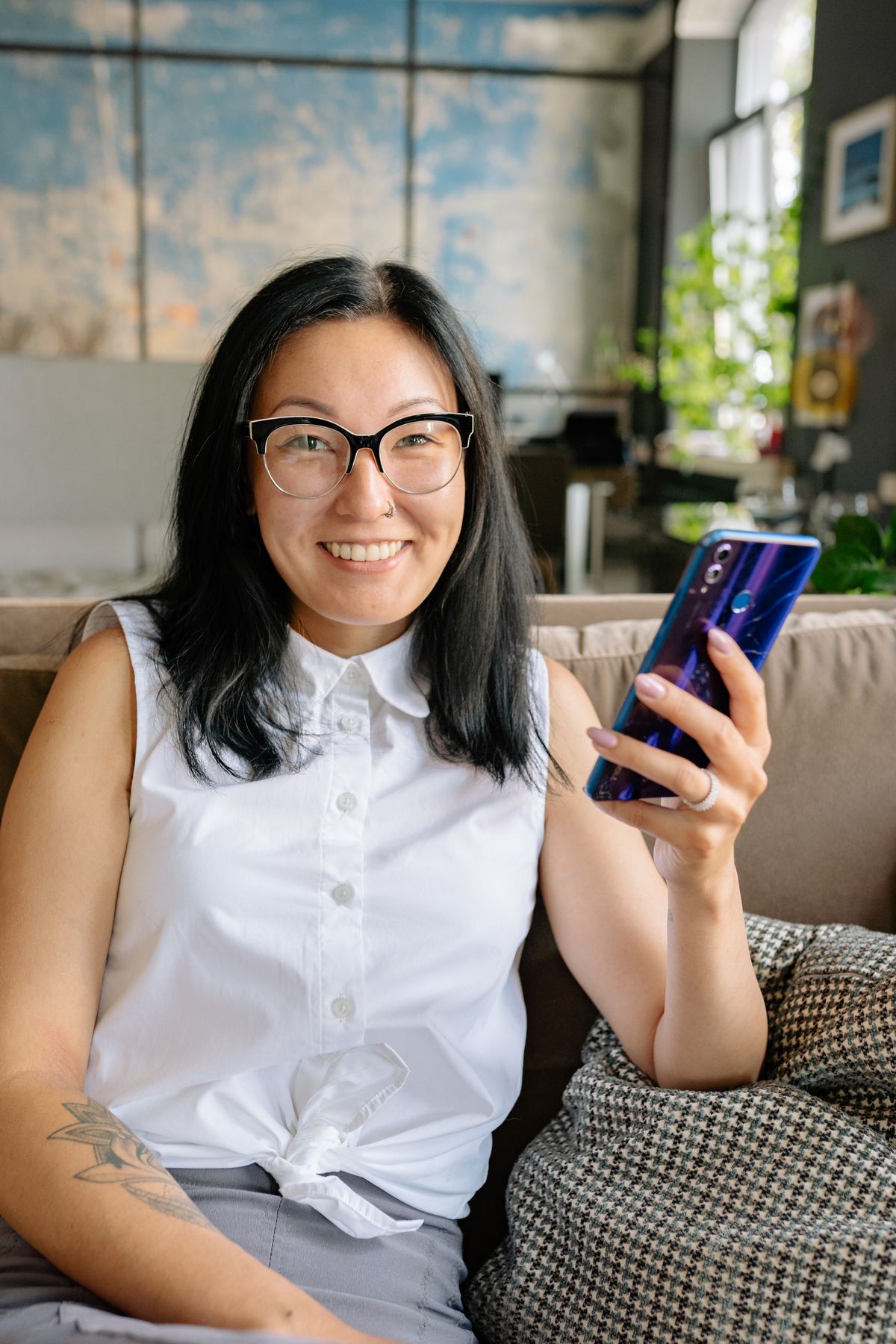 A woman on a sofa smiling at her phone