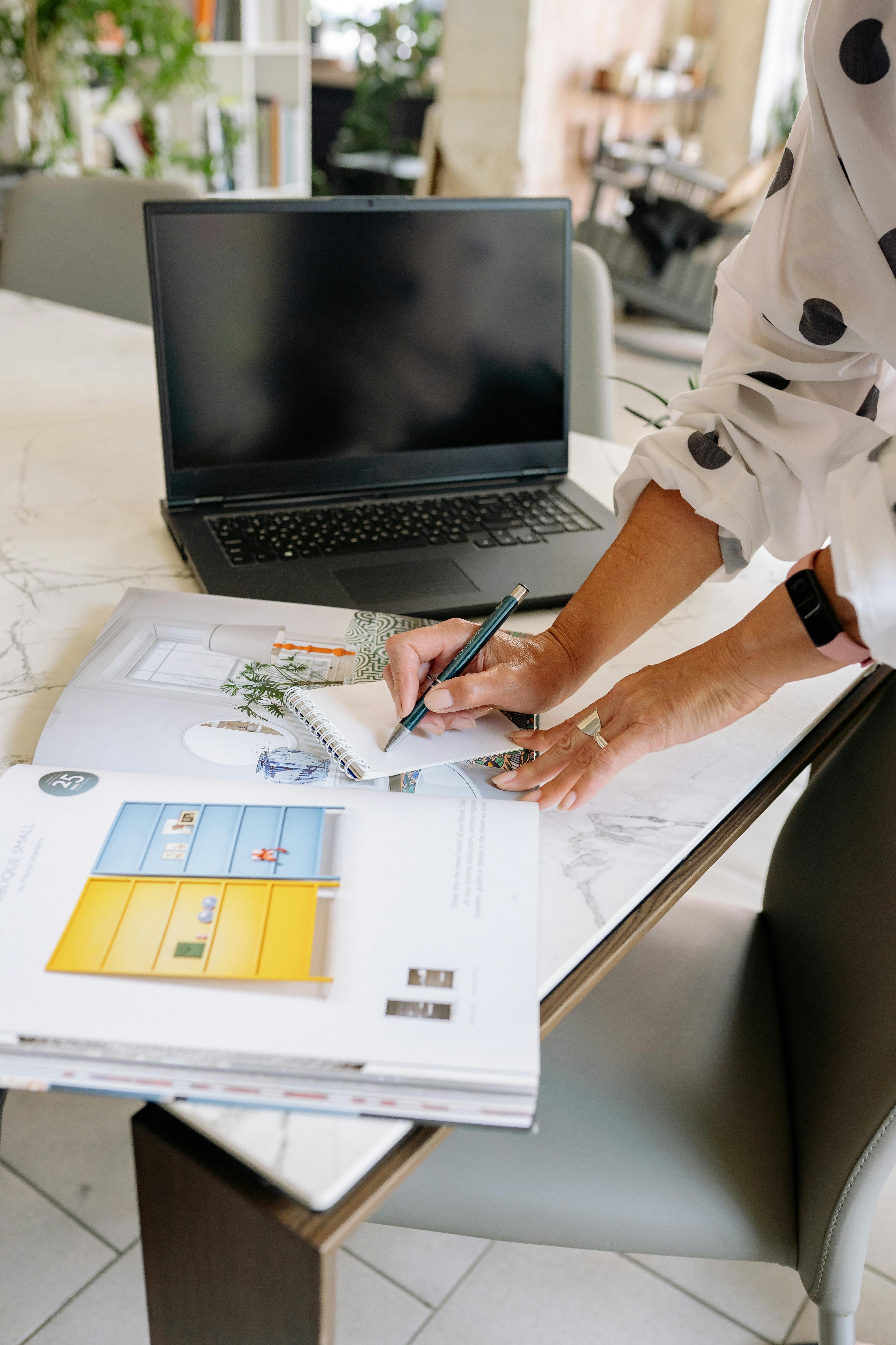 Free Woman Taking Notes in Notepad on Table in Office Stock Photo