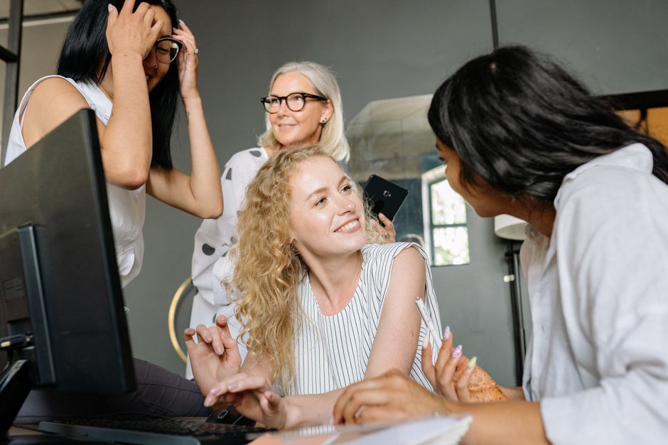 A dynamic group of diverse businesswomen collaborating in an office, sharing ideas and smiling.