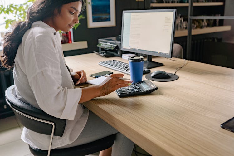 Woman Using A Calculator While Working