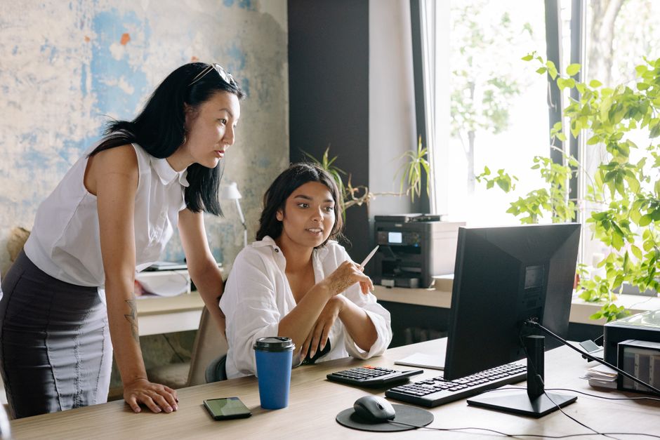 Two women collaborate in a bright office setting, fostering teamwork and innovation.