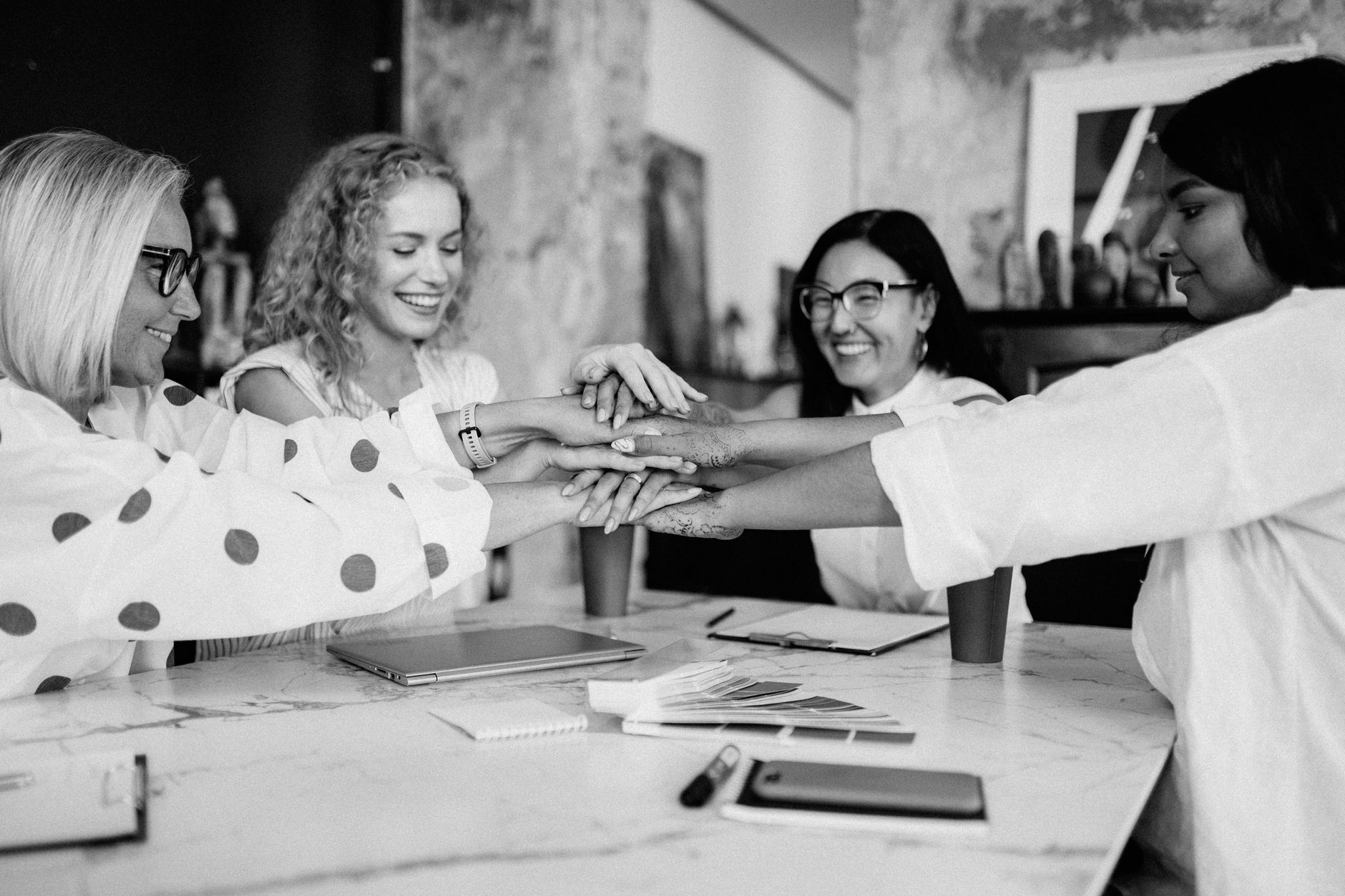 A joyful group of diverse women sharing a teamwork moment with hands together.