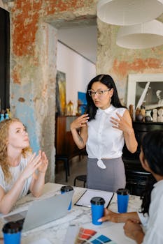 Three diverse women brainstorming in a creative workspace with laptops and coffee.