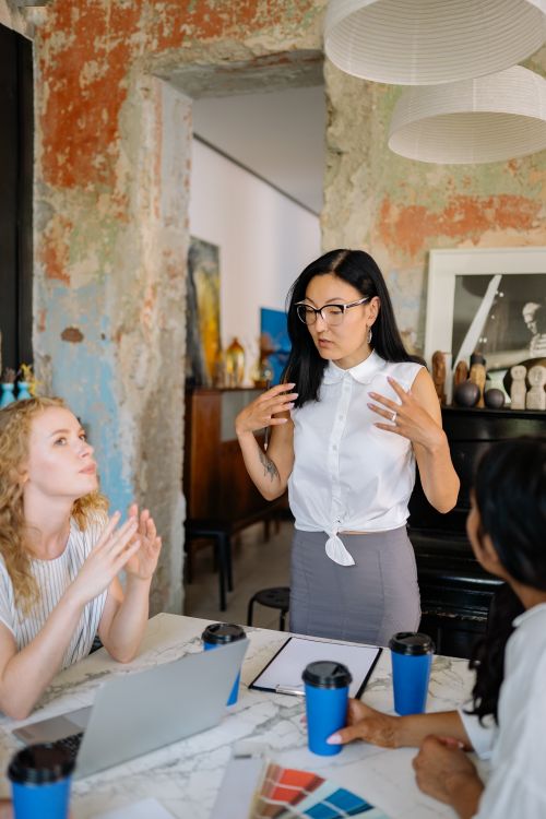 Free Three diverse women brainstorming in a creative workspace with laptops and coffee. Stock Photo