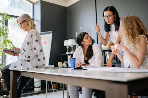 Free A diverse group of women engaged in teamwork and discussion inside a modern office space. Stock Photo