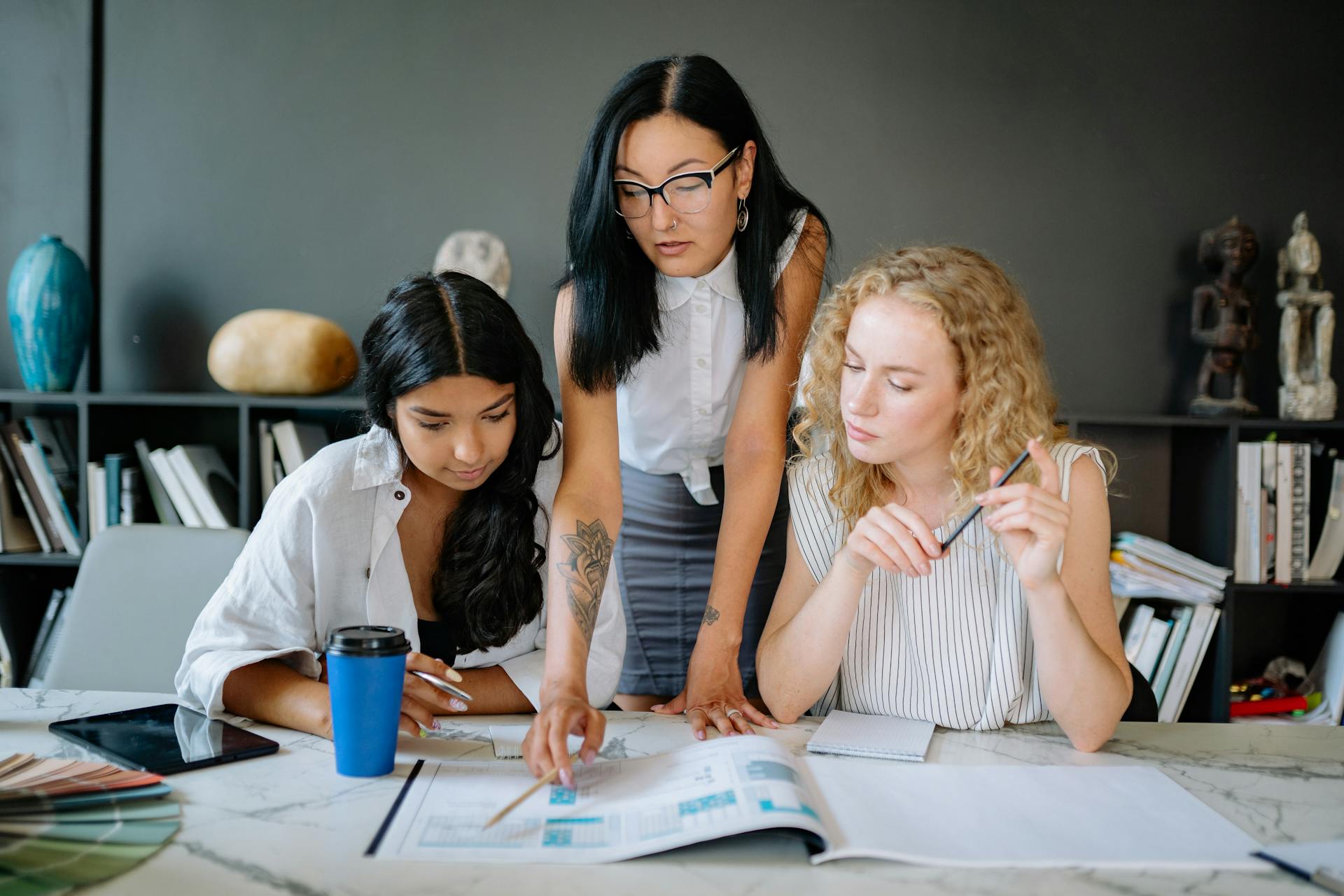 A Woman Wearing Eyeglasses Explaining the Project to the Employees Sitting Between Her