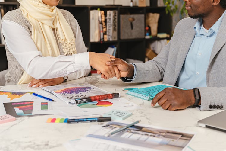 Man And Woman Shaking Hands Over Messy Table