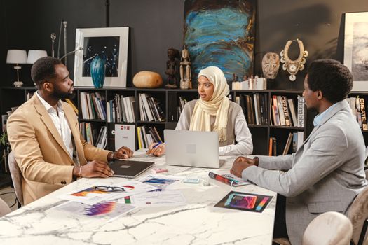 A diverse team working together on a project in a creative office setting, engaging in productive discussion.